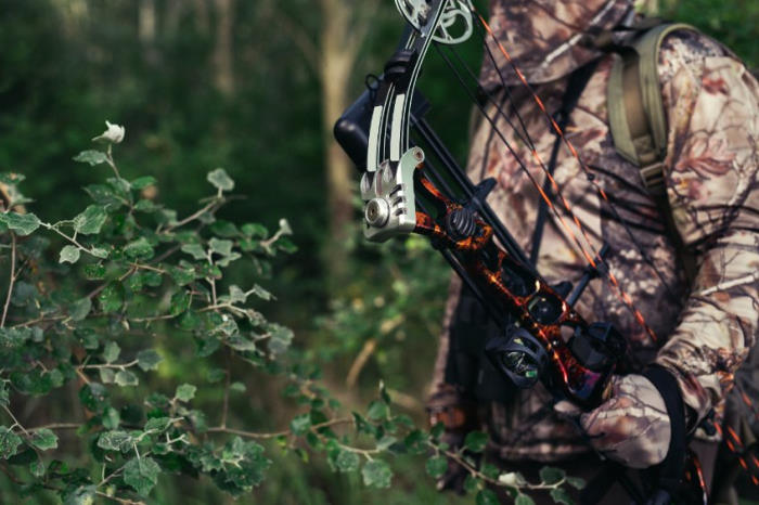 Guy with bow in camo in the woods
