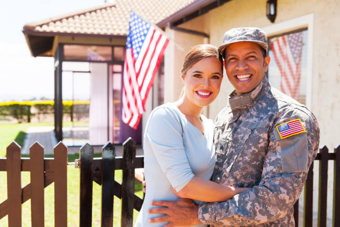 Army couple hugging by a home