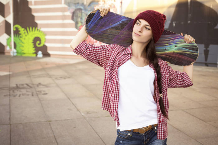 Brunette teenage tomboy holding skateboard
