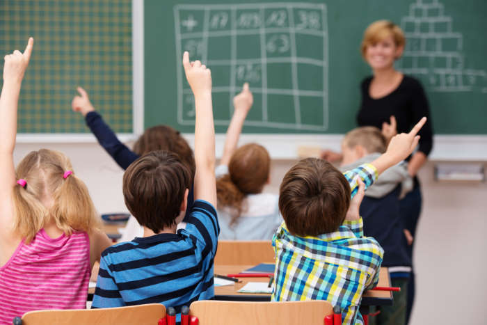 Children raising hand and teacher to give end of year gifts