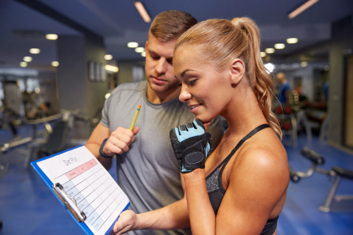 personal trainer and a woman looking at progress chart