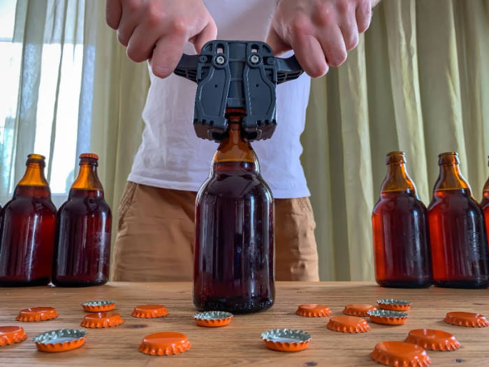 Guy homebrewing beer and putting caps on bottles
