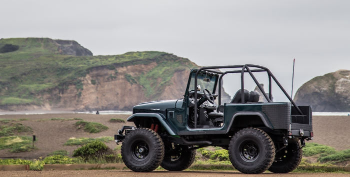 Jeep off road by large hill and water