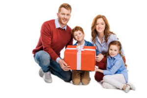 little sister giving gift to her brother with mom and dad there